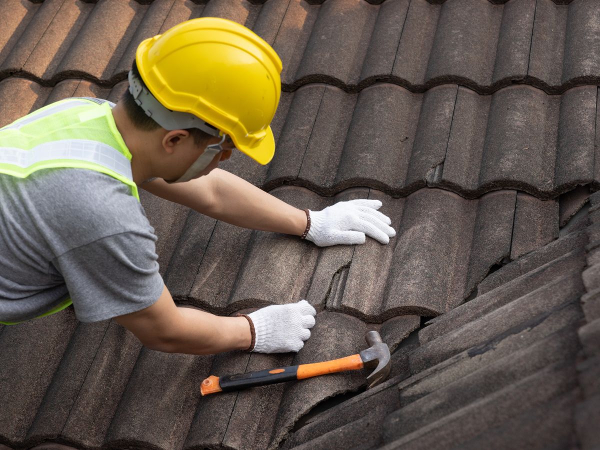 Roofer performing roof maintenance on tiles