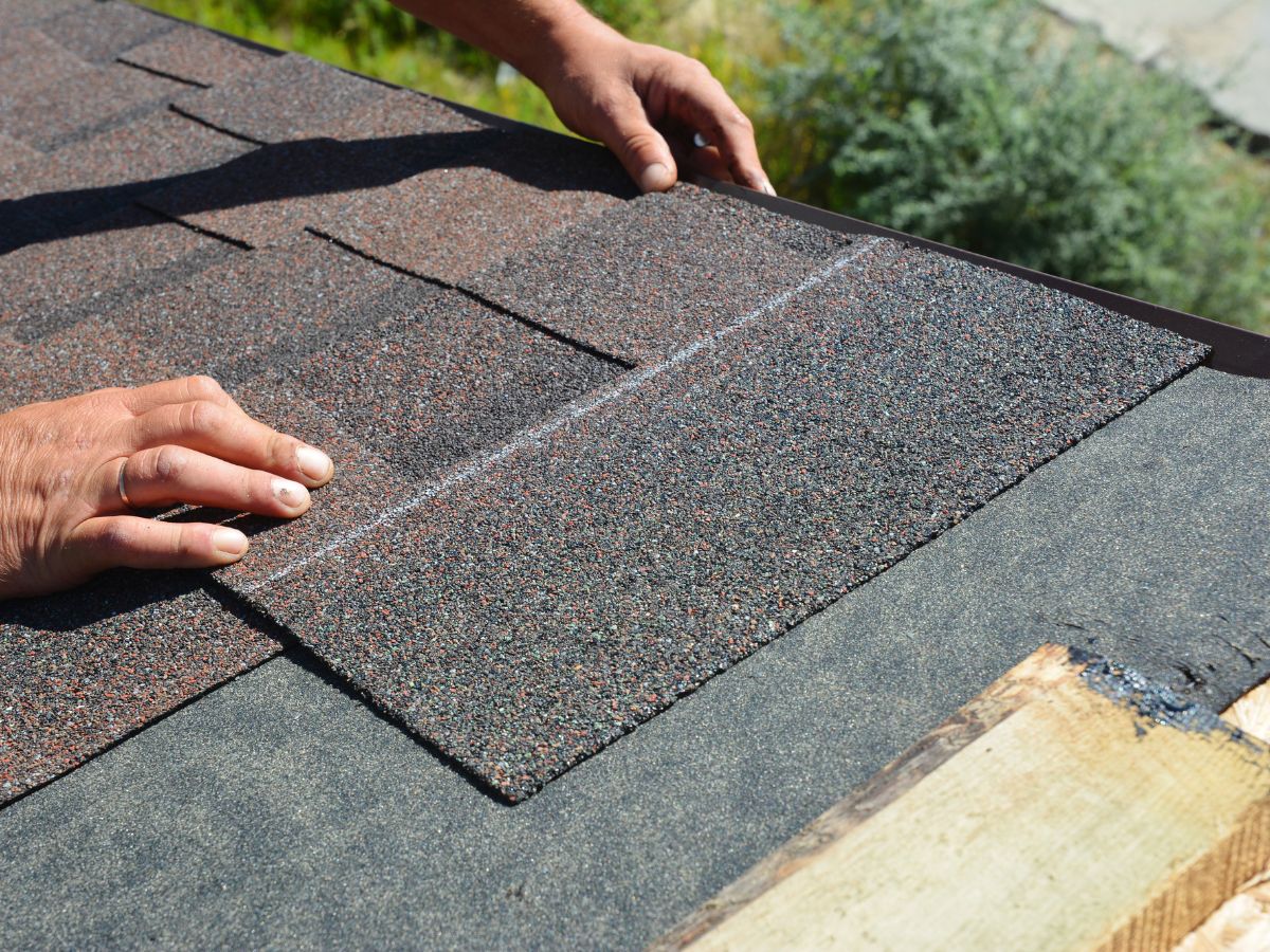Roofer repairs missing shingles on the asphalt roof