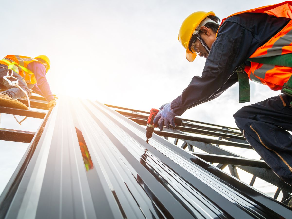 Roofers installing metal panels to extend roof's lifespan