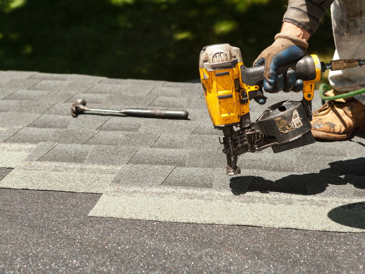 Fixing missing shingles with a nail gun on the roof