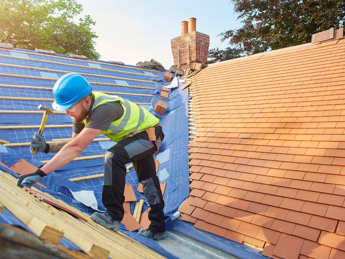 Roofer replacing tiles to extend roof's lifespan